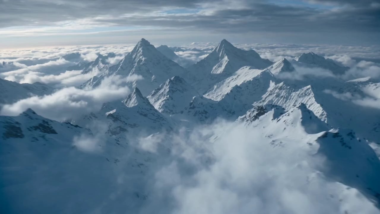 Snow-covered mountain peaks rise above a sea of clouds.