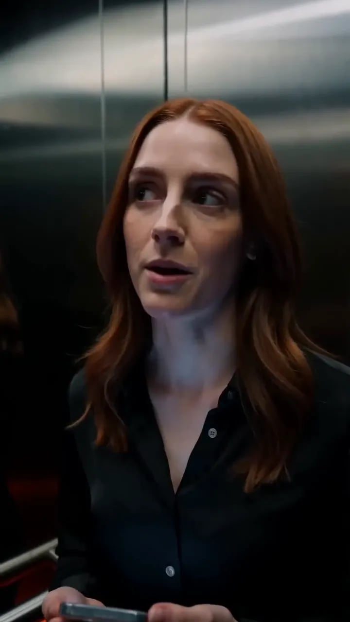 A woman and a man trade looks in a stalled elevator car.