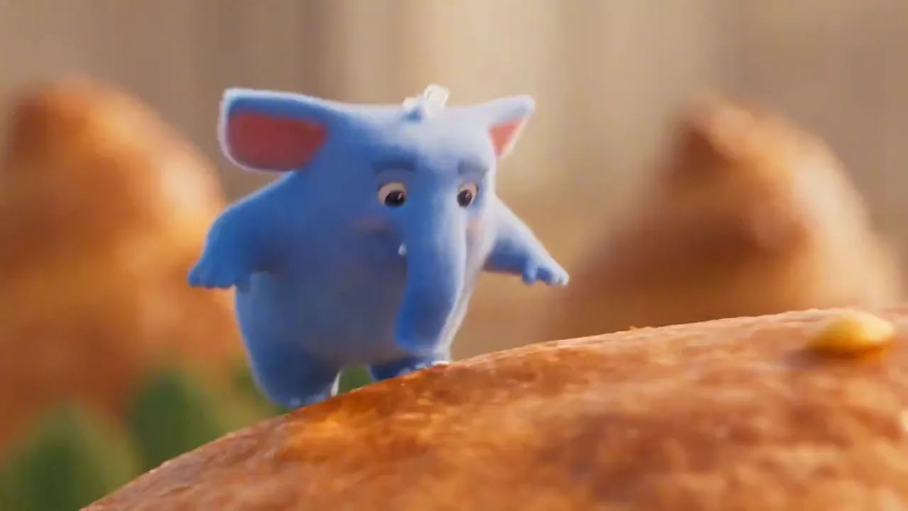 A small blue elephant hops across a landscape made of pastries and fruit.